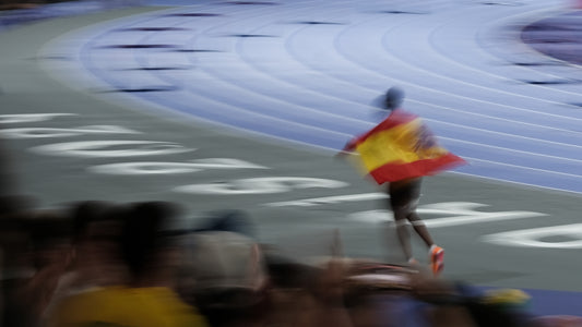 A man holding a spanish flag on top of a race track
